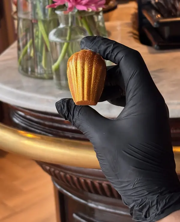 De hand van de chef met een gouden madeleine