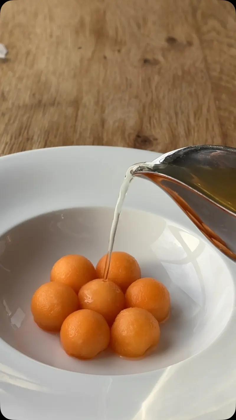 Tomatenconsommé wordt over bolletjes cantaloupe geschonken